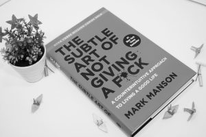 mark manson book (the subtle art of not giving a f*ck) on a table - learn 10 lessons from him for your creative work