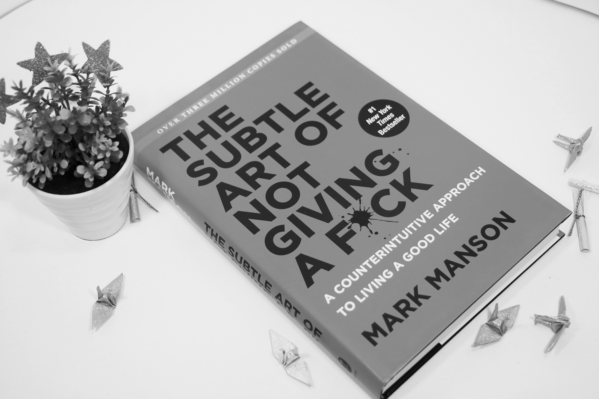 mark manson book (the subtle art of not giving a f*ck) on a table - learn 10 lessons from him for your creative work