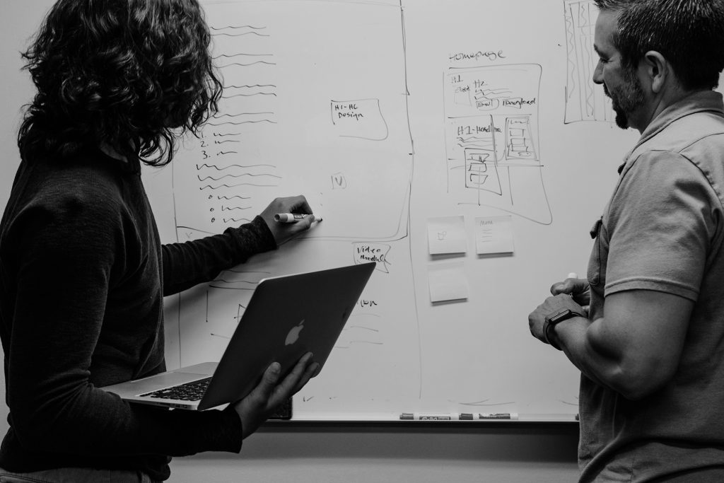 two people collaborating on a project, using a whiteboard - learn about writing briefs and collaborating with a writer