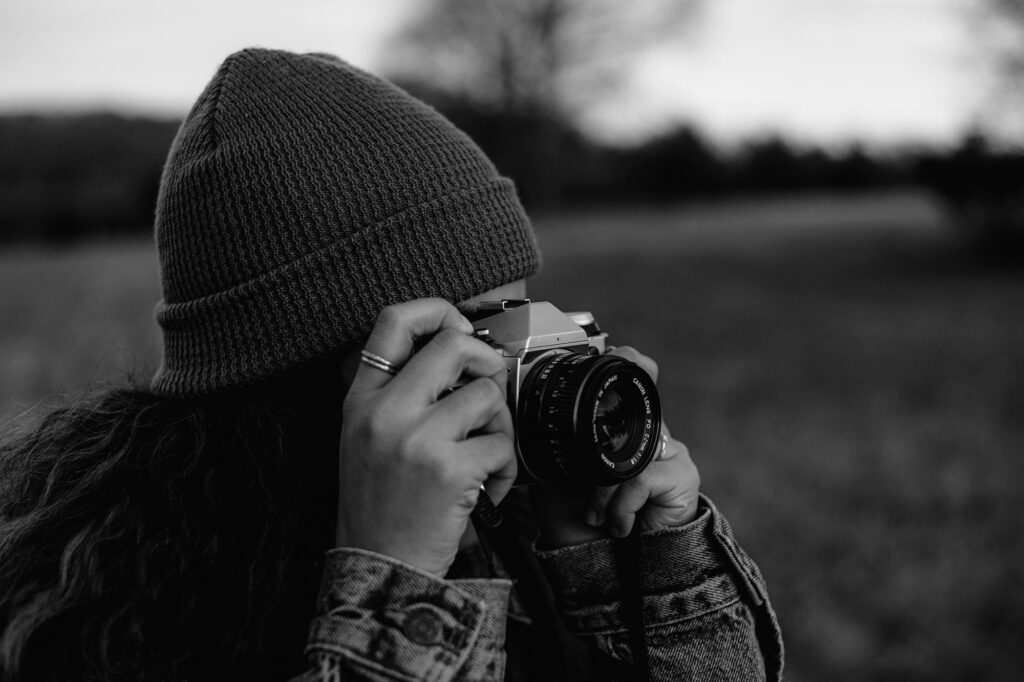 a person, holding a camera to her eyes, makes you wonder how to become a photographer