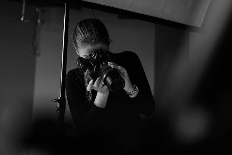 person looking through a camera viewfinder - learn how to take sharp photos