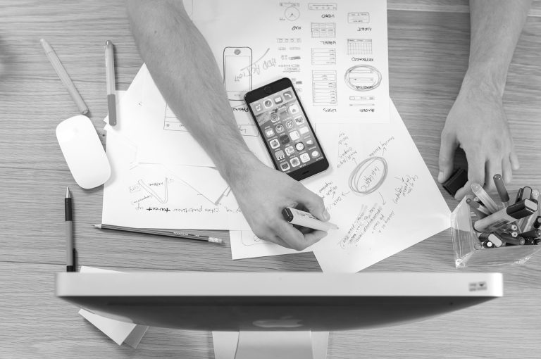 person with notes and a phone in front of a computer - learn about storytelling in marketing campaigns