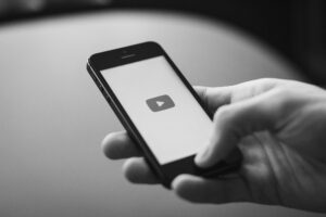 person holding a phone with youtube app opening -best photography and filmmaking youtube channels